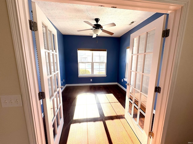 spare room with ceiling fan, french doors, dark hardwood / wood-style floors, and a textured ceiling