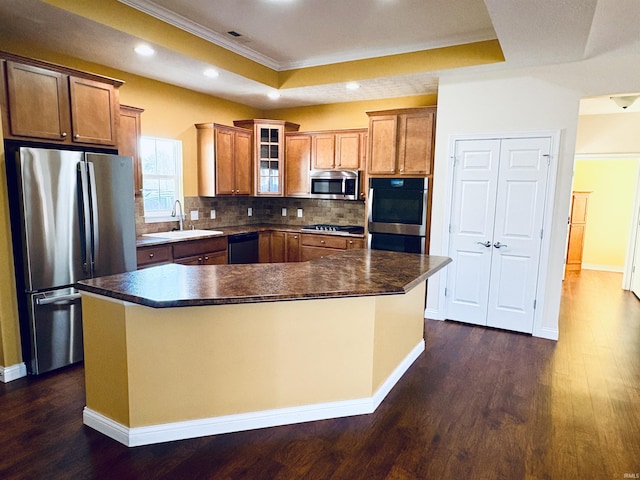 kitchen with sink, stainless steel appliances, tasteful backsplash, a tray ceiling, and a kitchen island