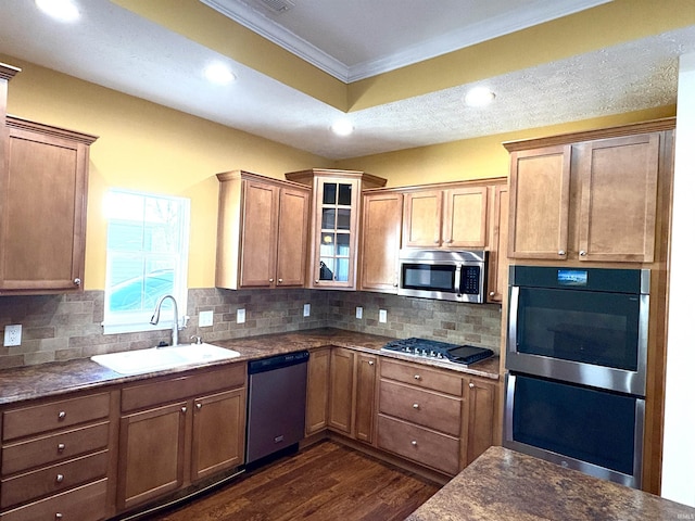 kitchen with dark wood-type flooring, sink, ornamental molding, appliances with stainless steel finishes, and tasteful backsplash