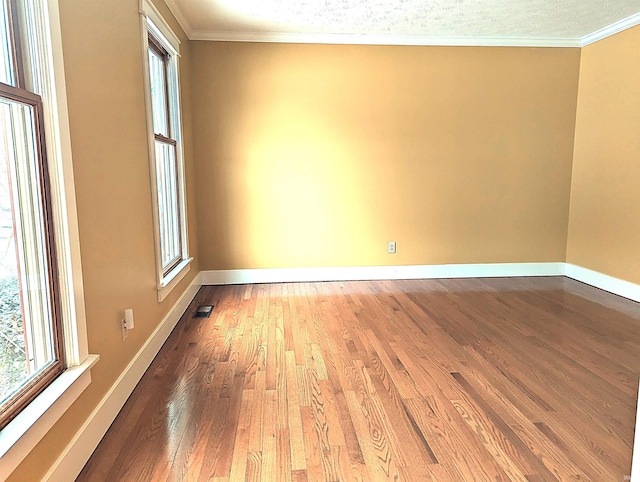 empty room featuring plenty of natural light, hardwood / wood-style floors, and ornamental molding