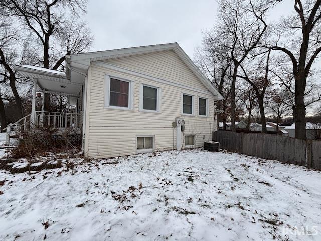 snow covered rear of property with a porch