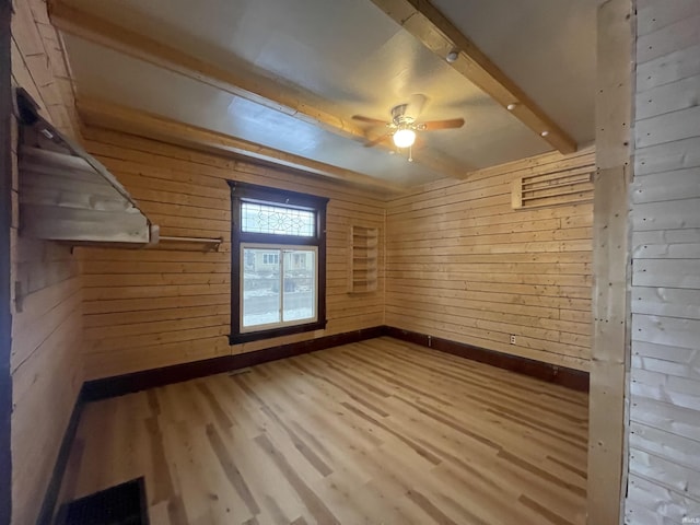 spare room with beam ceiling, wood walls, ceiling fan, and hardwood / wood-style flooring