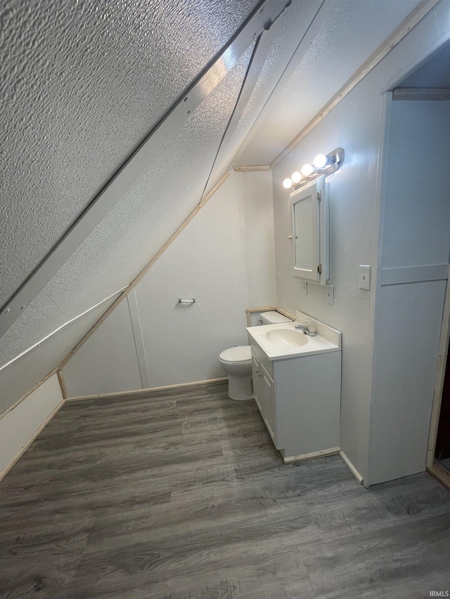 bathroom featuring vanity, wood-type flooring, lofted ceiling, and toilet