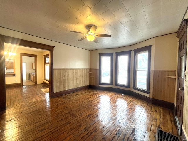 spare room with ceiling fan, wood walls, and dark hardwood / wood-style floors