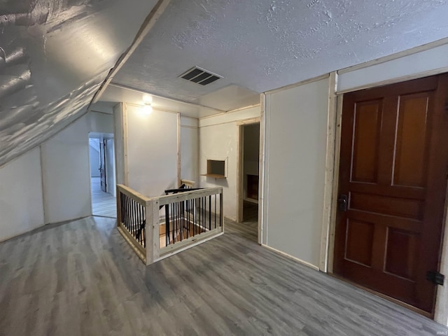 bonus room featuring a textured ceiling, wood-type flooring, and lofted ceiling