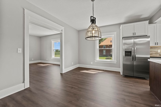 kitchen featuring pendant lighting, white cabinets, stainless steel refrigerator with ice dispenser, a wealth of natural light, and tasteful backsplash