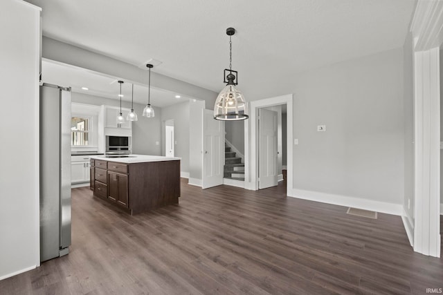 kitchen featuring dark brown cabinetry, a center island, hanging light fixtures, dark wood-type flooring, and stainless steel fridge