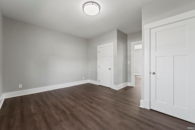 unfurnished bedroom featuring a textured ceiling, a closet, and dark hardwood / wood-style floors