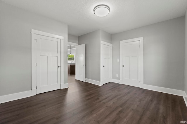 unfurnished bedroom with a textured ceiling and dark wood-type flooring