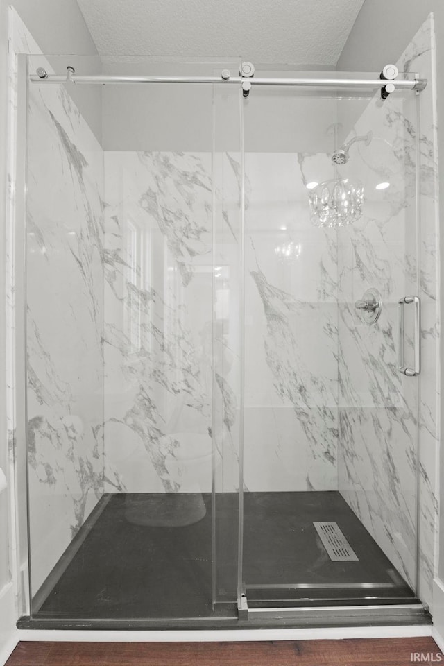 bathroom with a shower with shower door and a textured ceiling