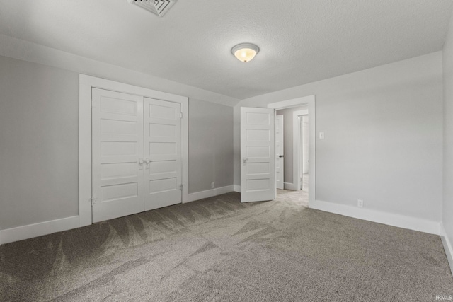 unfurnished bedroom featuring a textured ceiling, carpet floors, and a closet