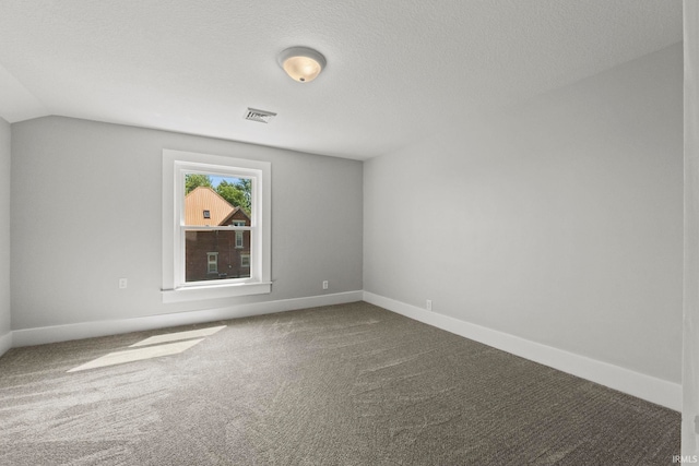 carpeted empty room featuring a textured ceiling and vaulted ceiling