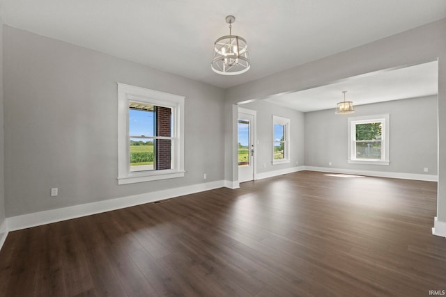 unfurnished room featuring a chandelier and dark wood-type flooring