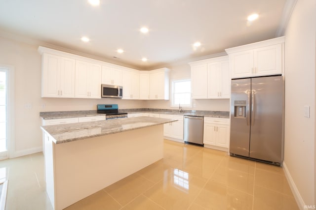 kitchen featuring a center island, sink, stainless steel appliances, light tile patterned floors, and white cabinets