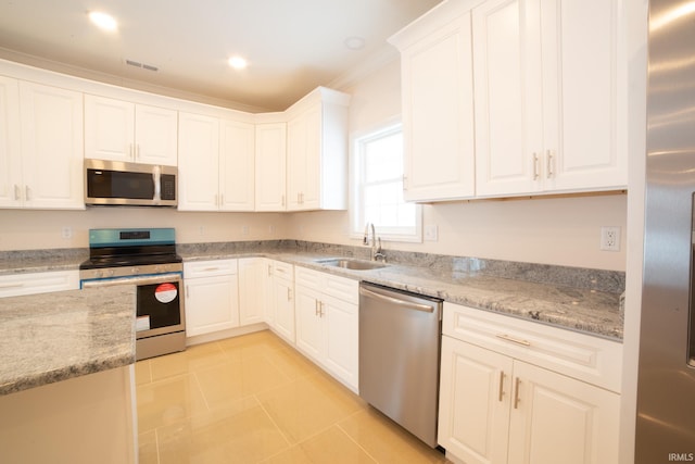 kitchen featuring white cabinetry, sink, light stone counters, and appliances with stainless steel finishes