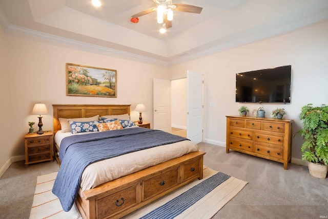 bedroom with light colored carpet, a raised ceiling, and ceiling fan