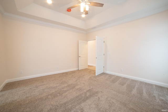 carpeted spare room featuring a tray ceiling, ceiling fan, and ornamental molding