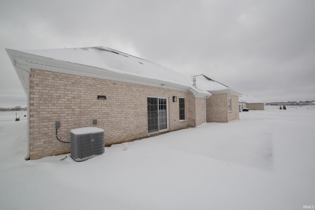 snow covered back of property with cooling unit