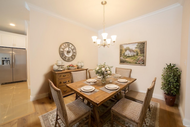 dining area with light hardwood / wood-style flooring, a notable chandelier, and crown molding