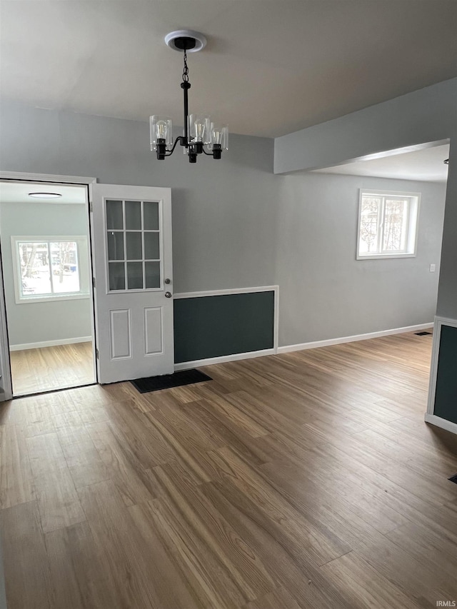 unfurnished dining area featuring hardwood / wood-style floors and an inviting chandelier