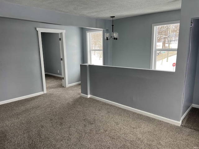 empty room featuring carpet flooring, a chandelier, and a textured ceiling