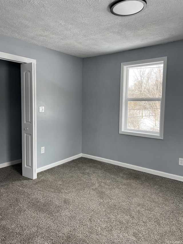 spare room with dark colored carpet and a textured ceiling