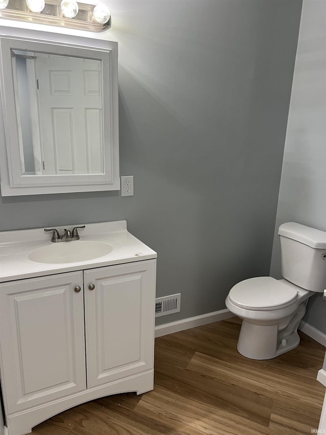 bathroom with wood-type flooring, vanity, and toilet