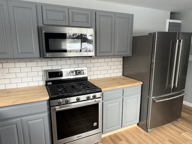 kitchen featuring gray cabinets, light hardwood / wood-style flooring, appliances with stainless steel finishes, and wooden counters