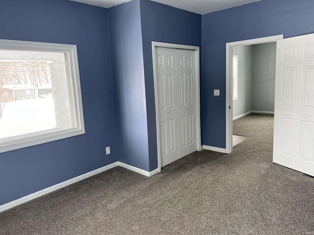 unfurnished bedroom with dark carpet and a closet