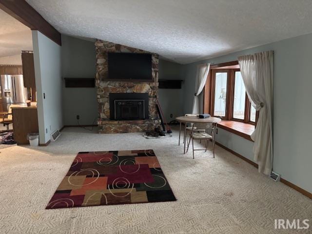 living room with a textured ceiling, a stone fireplace, and lofted ceiling