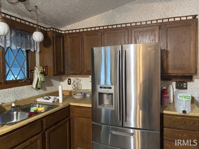 kitchen featuring stainless steel fridge, a textured ceiling, lofted ceiling, and sink