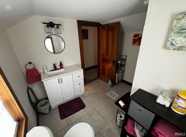 bathroom with vanity, vaulted ceiling, and toilet