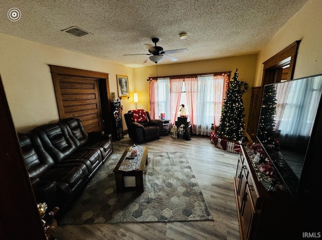 living room with ceiling fan, light hardwood / wood-style floors, and a textured ceiling