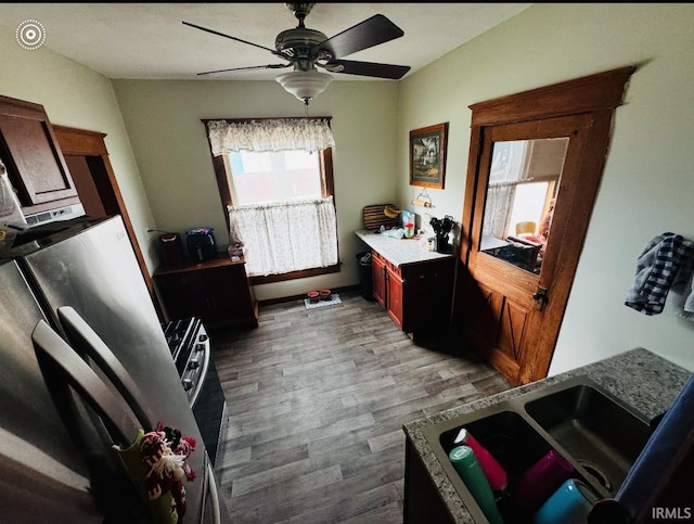 kitchen with ceiling fan, light stone counters, and light hardwood / wood-style flooring