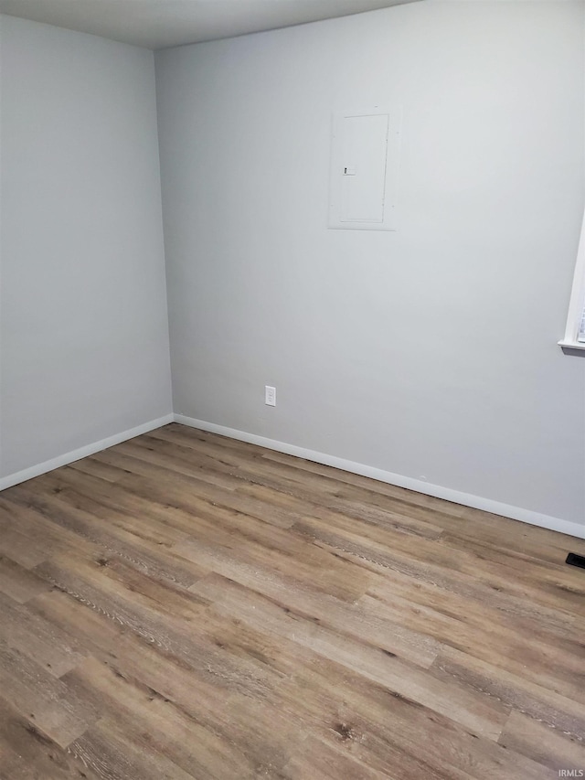 spare room featuring electric panel and light hardwood / wood-style flooring