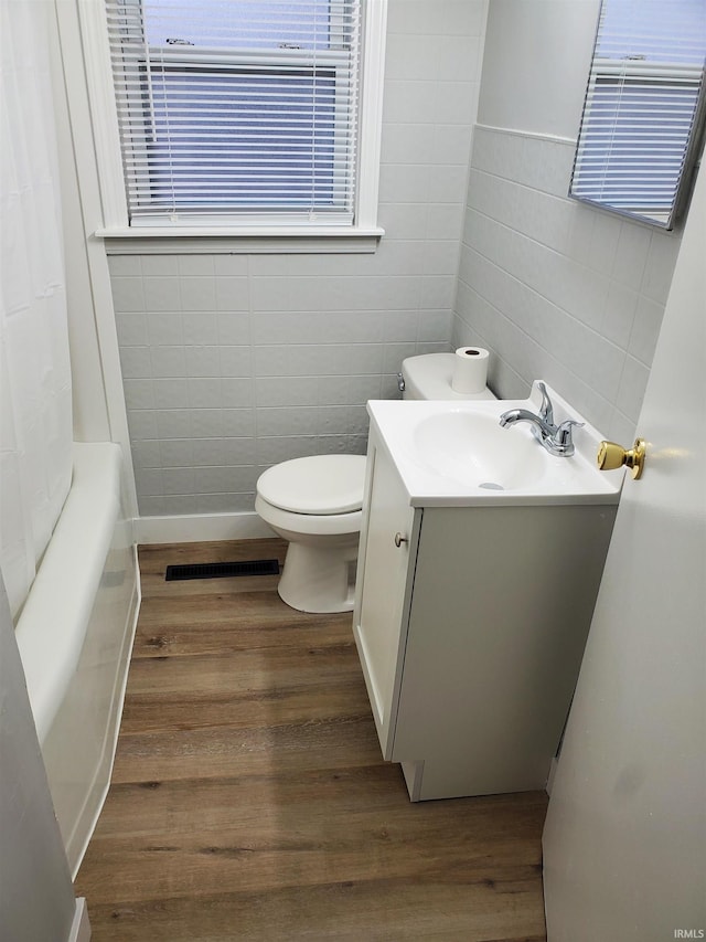 full bathroom with hardwood / wood-style flooring, vanity, toilet, and shower / bathtub combination with curtain