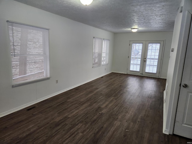 empty room featuring french doors, a textured ceiling, and dark hardwood / wood-style floors