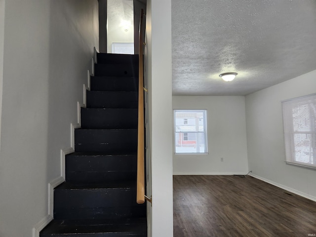 stairway featuring wood-type flooring and a textured ceiling