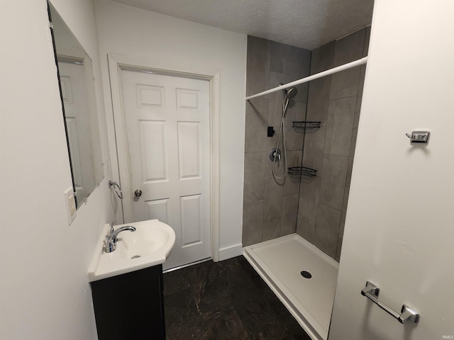 bathroom with a tile shower, vanity, and a textured ceiling