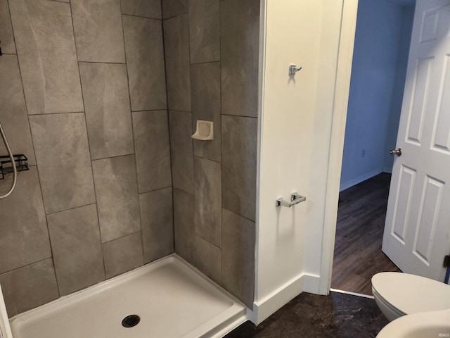 bathroom with hardwood / wood-style floors, toilet, and tiled shower