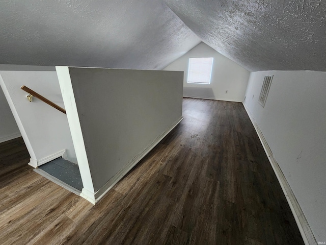 bonus room featuring a textured ceiling, vaulted ceiling, and dark wood-type flooring