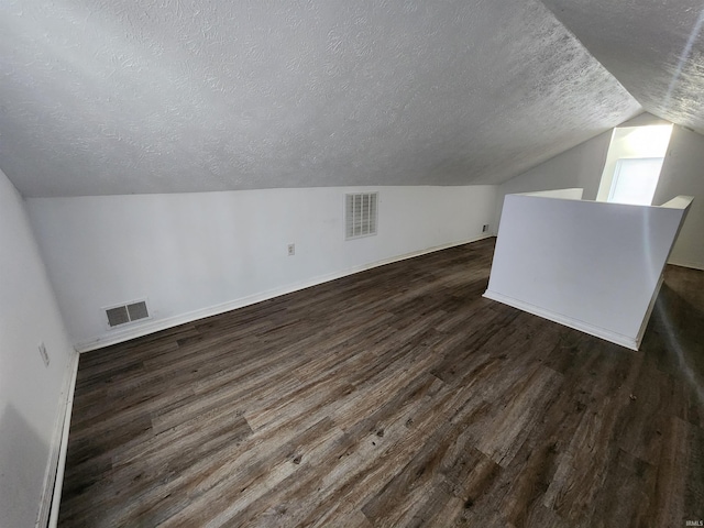 additional living space with a textured ceiling, dark hardwood / wood-style floors, and lofted ceiling