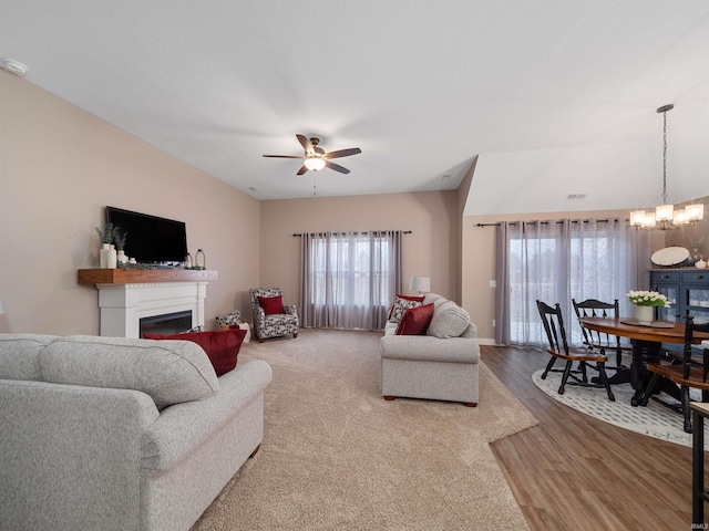 living room featuring ceiling fan with notable chandelier and light hardwood / wood-style floors