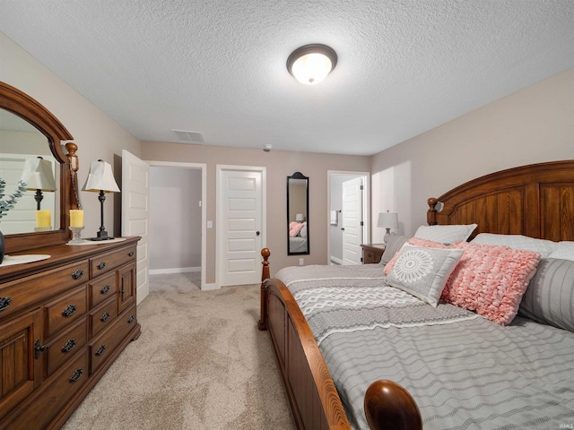 bedroom with light colored carpet and a textured ceiling