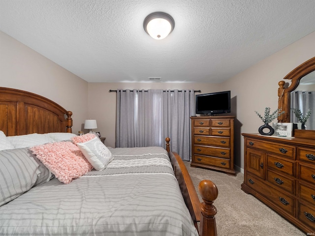 bedroom featuring light colored carpet and a textured ceiling