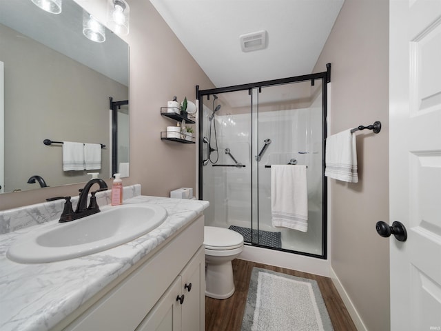 bathroom featuring vanity, toilet, wood-type flooring, and walk in shower