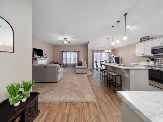 living room with ceiling fan, sink, and light wood-type flooring