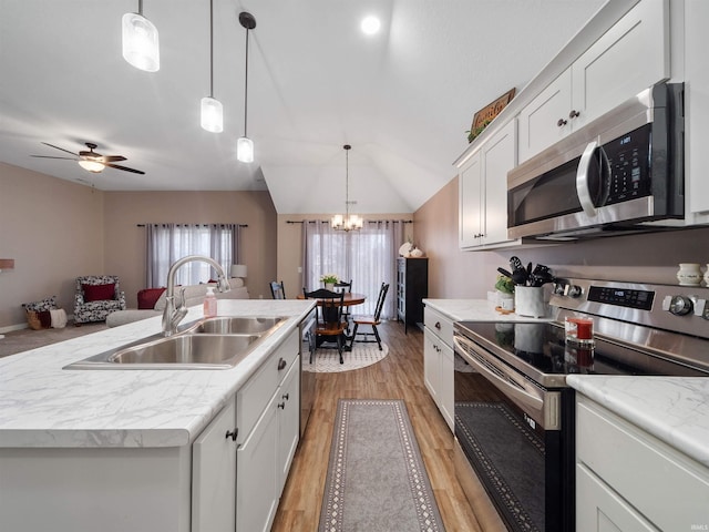 kitchen with hanging light fixtures, appliances with stainless steel finishes, a kitchen island with sink, and sink