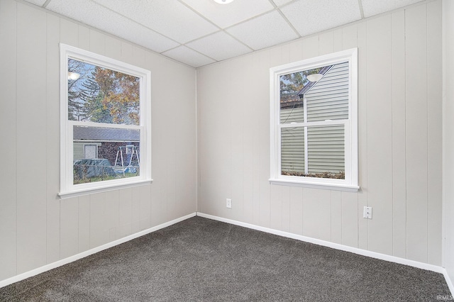 empty room featuring a paneled ceiling and dark carpet