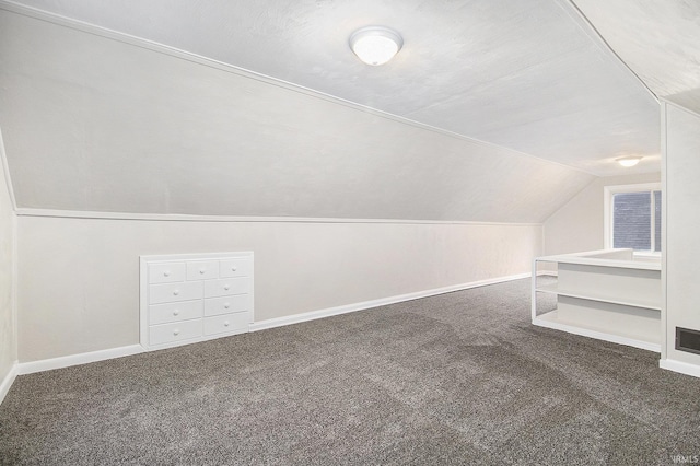 bonus room with dark carpet, a textured ceiling, and vaulted ceiling